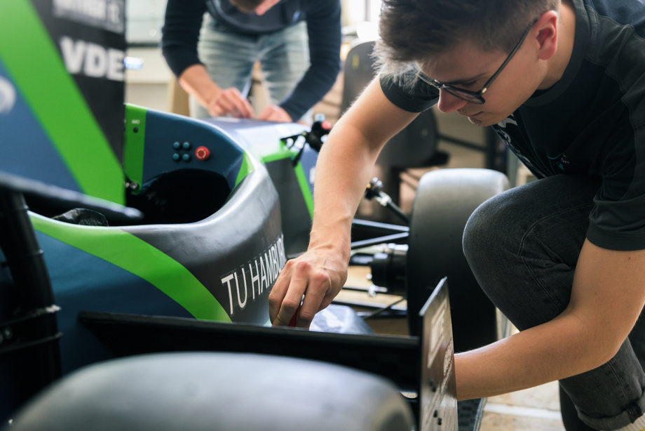 Ein Studierender, der an einem Rennauto des Teams E-gniton der TUHH herumschraubt