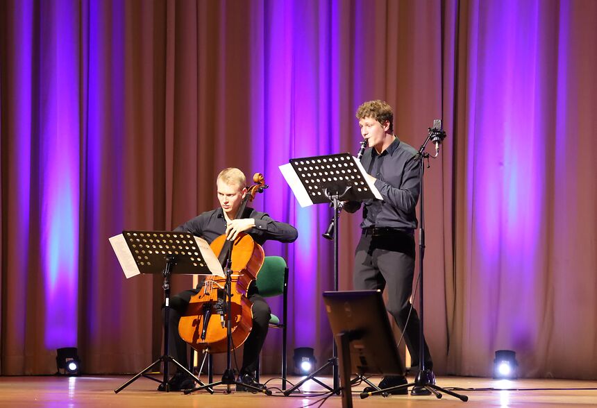 zwei junge Männder musizieren auf der Bühne. Einer spielt Cello, der andere Klarinette